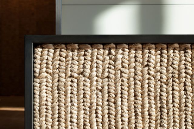 Close-up detail of a custom desk with a woven cane front and dark wood frame.